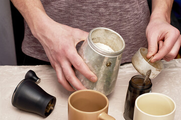 Fototapeta na wymiar a man makes coffee in a geyser sets a strainer for ground coffee in a geyser