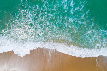 Fototapeta na wymiar Aerial view sandy beach and waves crashing on sand. Beautiful tropical sea in the morning summer season image by Aerial view drone shot, high angle view Top down