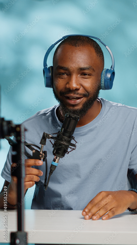 Poster vlogger using smartphone to record video for vlog channel with microphone, laptop and headphones. bl