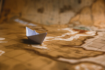 White paper ship on geographical map background.