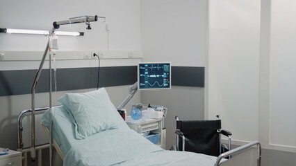 Nobody in hospital ward with bed and heart rate monitor for reanimation and healthcare. Empty emergency room with medical instruments and equipment for intensive care. Space for recovery
