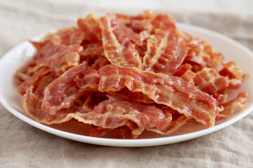 Crispy Fried Bacon on a white plate, side view.