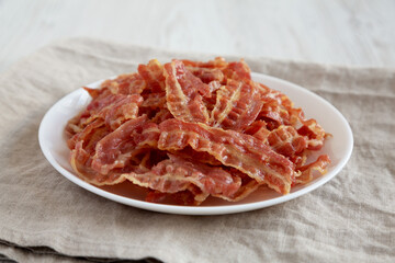 Crispy Fried Bacon on a white plate, side view.