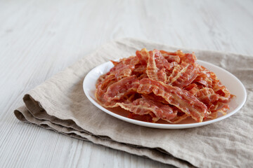 Crispy Fried Bacon on a white plate, side view. Space for text.