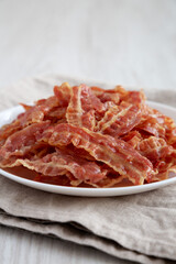 Crispy Fried Bacon on a white plate, side view. Close-up.