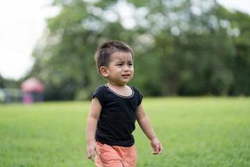 Asian little toddler boy is crying while he is walking alone in the park, concept of emotional expression of kid for scare, lonely, worry, upset, stress, depress in the childhood.