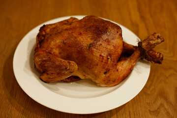 Roast chicken breast-down placed on white plate dish