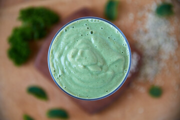 A green smoothie restores my body to factory settings. Overhead shot of a green health smoothie on a wooden board.