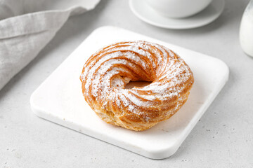 Rings of custard cakes with cottage cheese cream on a marble board on a grey background with a cup of tea