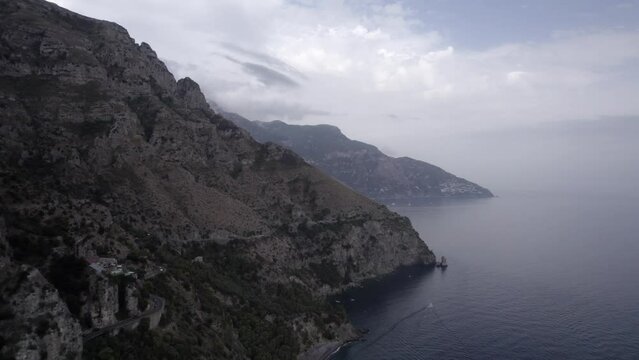 Drone video over the Amalfi Coast near Positano flying over the cliff with a frontal plane advancing in the direction of Positano.
Sky with clouds boats and vehicles can be seen.