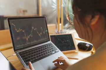 Asian Businesswoman, female trader, investor using laptop, tablet for stock market, Bitcoin cryptocurrency trading, strategy planning on money investing on online trading platform. Trading concept. - 495585874