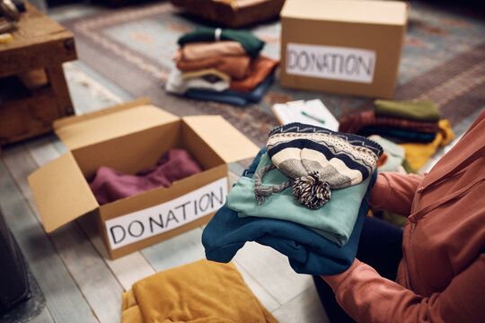Close Up Of Woman Packing Warm Clothes In Donation Boxes For Charitable Foundation.