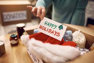Close-up of volunteer adding Christmas greeting card into donation dox. © Drazen