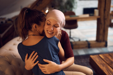 Happy cancer patient embraces her friend who is visiting her at home.
