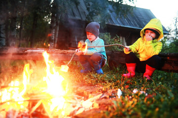 Naklejka na ściany i meble Little children frying marshmallows on bonfire at night. Summer camp