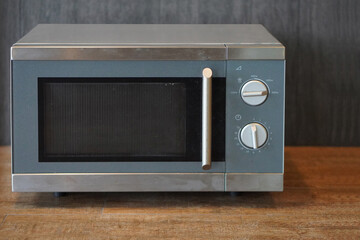  front view old grey and silver microwave oven on wooden floor background, decor, technology, fashion, copy space