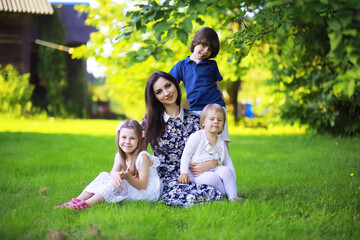 Obraz premium Young large family on a summer morning walk. Beautiful mother with children is playing in the park.