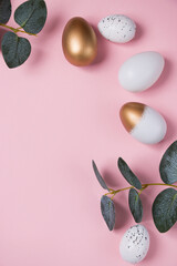 Easter eggs with green eucalyptus branches on a pink background. Holiday concept. Happy Easter greeting card