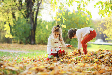 Children for a walk in the autumn park. Leaf fall in the park. Family. Fall. Happiness.