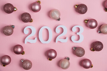 White numbers 2023 with Christmas balls on a pink background. Christmas and New Year card.