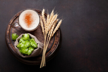 Lager beer mug, hops and wheat on old wooden barrel