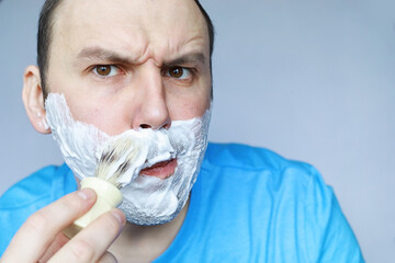 A man shaves in front a mirror. Shaving foam. Disposable razor.