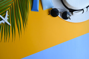 Flat lay sunglasses, hat, sunscreen bottles and tropical palm leaves. Summer vacation concept.