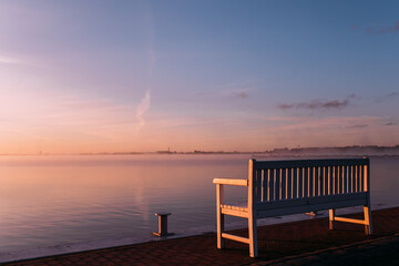 Fototapeta na wymiar einzelne Bank am Meer bei Sonnenaufgang strahlt tiefe Ruhe aus 