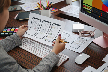 Fototapeta na wymiar UX designer planning application template layout framework for mobile phone at office desk.