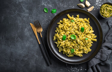 Fusilli pasta and basil pesto sauce on a black background.