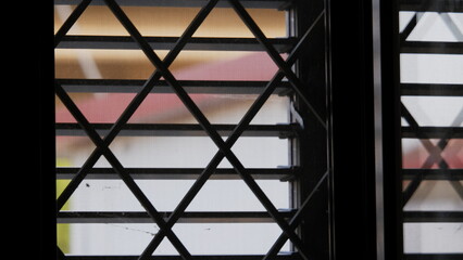 A lattice window in a rural house with the blind down and a folded awning