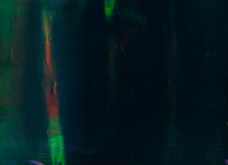 Green lens flare. Old filmstrip texture. Blur gleam on dark background.
