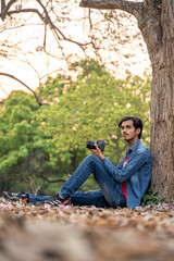 Fototapeta premium Photographer holding a camera sitting under the tree