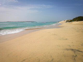 Sandy beach in Cape Verde. Tropical climate, bright blue sky, turquoise water of Atlantic Ocean and vacation mood. Selective focus on the details, blurred background.