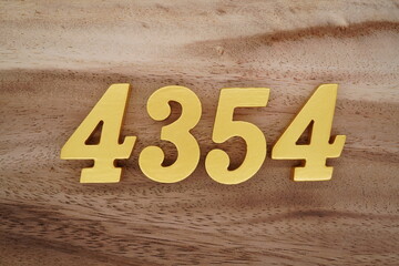 Golden Arabic numerals on a real brown and white wooden floor number 4354