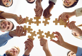 Happy successful business team putting together puzzle pieces during coaching training. Bottom view...