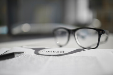 Crop close up of contract paperwork with glasses and pen ready for signature in office. Concept of signing agreement or closing deal with business partner. Negotiations and partnership.