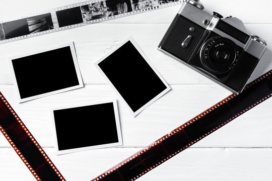 Old retro camera and photos on white wooden background