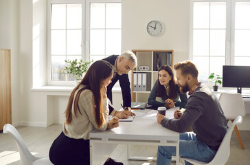 Diverse businesspeople gather at casual office meeting brainstorm cooperate about startup project. Colleagues or employees collaborate discuss business ideas together. Teamwork concept.