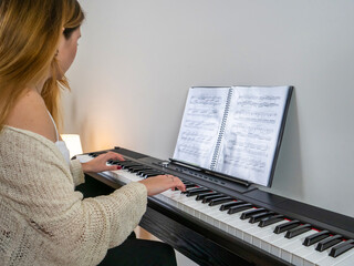 Young student playing piano in home