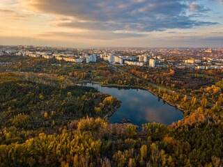Fototapeta premium Aerial view of a lake in a park with autumn trees. Kishinev, Moldova. Epic aerial flight over water. Colorful autumn trees in the daytime.