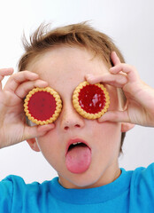 Funny kid holding two strawberry cookies on eyes.