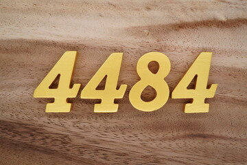 Golden Arabic numerals on a real brown and white wooden floor number 4484