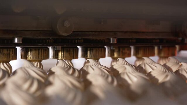 Automated line with rotating nozzles producing vanilla marshmallows. Close up. Food factory concept.