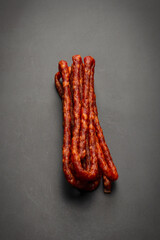 Cabanossi, dry sausage isolated on black background.