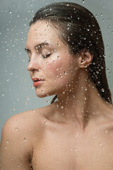 Naklejka premium Portrait of sensual woman captured through wet glass