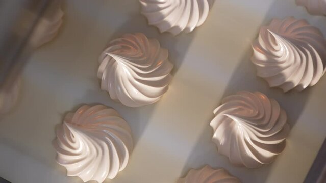 Beautifully shaped white creamy marshmallows moving slowly on conveyor belt. View from above. Close up.