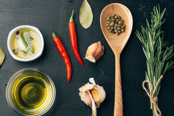 Wooden spoon and different spices on black background