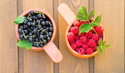 Two ceramic containers with raspberries and black currants