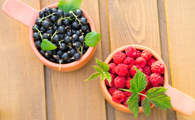 Two ceramic containers with raspberries and black currants